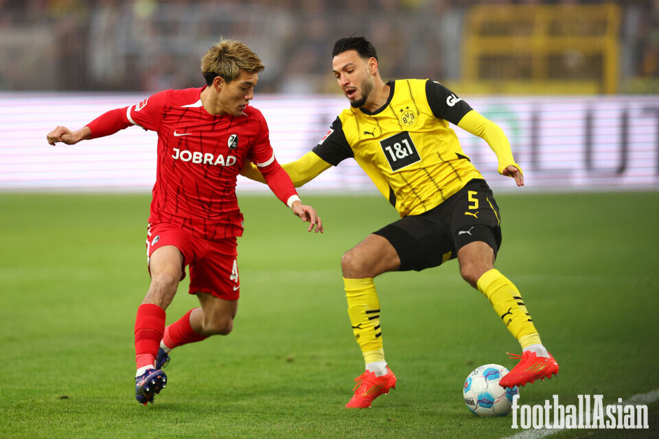 DORTMUND, GERMANY - NOVEMBER 23: Ritsu Doan of SC Freiburg challenges Ramy Bensebaini of Borussia Dortmund during the Bundesliga match between Borussia Dortmund and Sport-Club Freiburg at Signal Iduna Park on November 23, 2024 in Dortmund, Germany. (Photo by Dean Mouhtaropoulos/Getty Images)