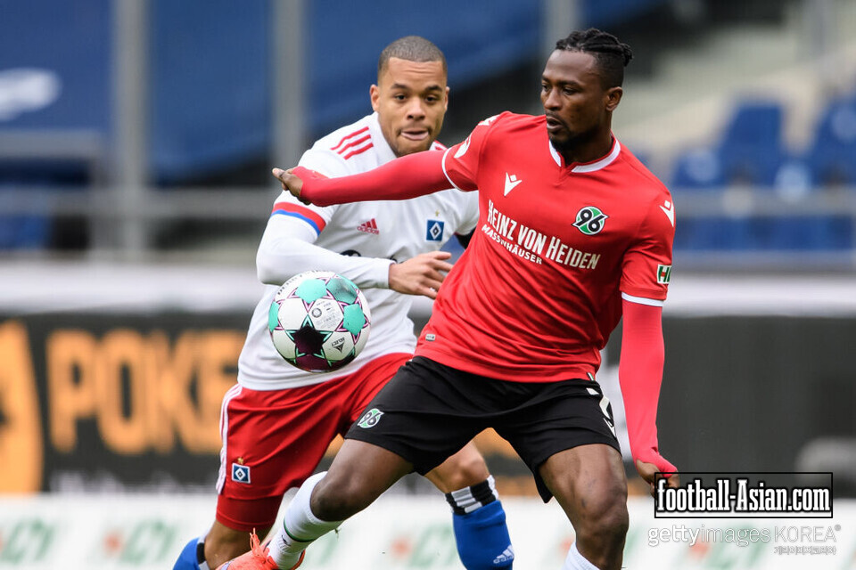 HANOVER, GERMANY - APRIL 04: Patrick Twumasi (R) of Hannover is challenged by Jan Gyamerah of Hamburg during the Second Bundesliga match between Hannover 96 and Hamburger SV at HDI-Arena on April 4, 2021 in Hanover, Germany. (Photo by Swen Pförtner - Pool/Getty Images )